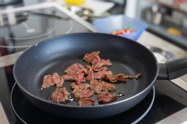 Şef kızartma tavasında dana eti kızartıyor.