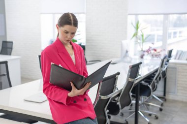 Beyaz iş kadını ofiste evrak okuyor.