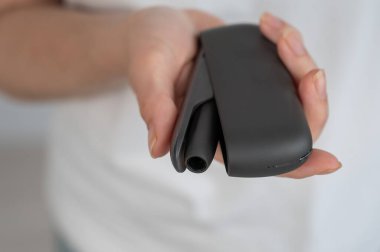 Bir kadın, tütün ısıtma sistemini şarj aletinden çıkarır. Elektronik sigara.