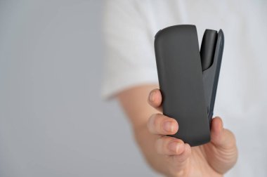 Bir kadın, tütün ısıtma sistemini şarj aletinden çıkarır. Elektronik sigara.