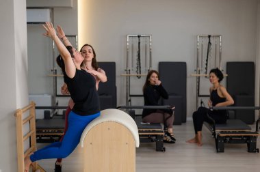 Pilates yapan üç kadın ve pilates yapan bir fıçı.