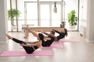 İki kadın ve bir erkek stüdyoda yoga yapıyorlar.