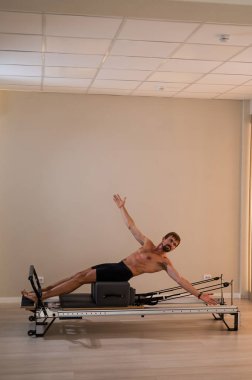 Reformcu üzerinde pilates yapan bir adam.