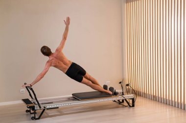 Reformcu üzerinde pilates yapan bir adam.