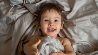 Beyaz tenli şirin bir çocuğun yatakta yatışının üst görüntüsü.
