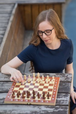 Beyaz kadın dışarıda satranç oynuyor.