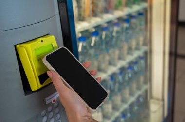 Cep telefonlu Modern Otomat Ödemesi. Bir kadın self-servis makinesinden bir şişe su alır.