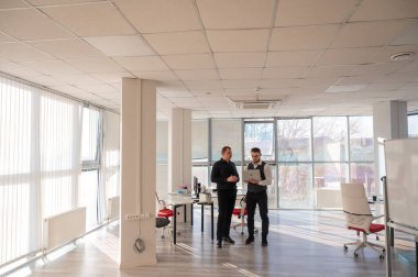 İki beyaz adam dizüstü bilgisayara bakıyor ve iş tartışıyorlar.