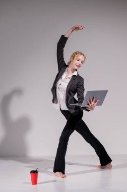 Beyaz arka planda iş elbisesiyle dans eden çıplak ayaklı balerin.