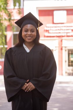 Mezuniyet elbisesi içinde mutlu bir Afrikalı kadın.