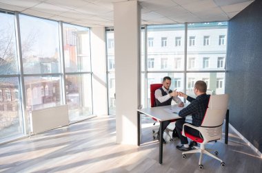 İki beyaz adam bir iş toplantısında birbirlerini selamlıyorlar.