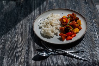 Tatlı ve ekşi soslu domuz eti ve tabakta haşlanmış pirinç.