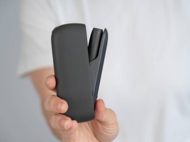 Bir kadın, tütün ısıtma sistemini şarj aletinden çıkarır. Elektronik sigara.