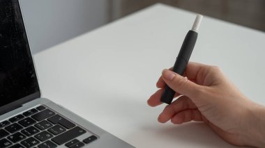 Bir kadın dizüstü bilgisayarla uğraşırken elektronik sigara içiyor. Tütün ısıtma sistemi