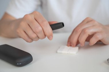 Bir kadın tütün ısıtma sistemine sigara çubuğu sokuyor. Elektronik sigara.