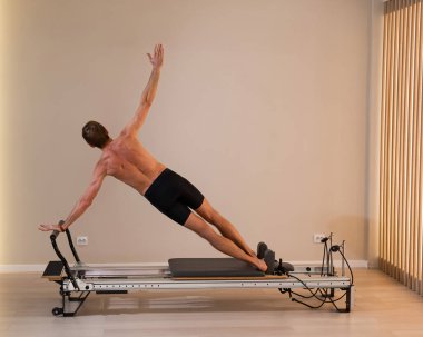 Reformcu üzerinde pilates yapan bir adam.