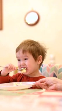 Şirin 1 yaşındaki çocuk kaşıkla tek başına yiyor. Dikey video