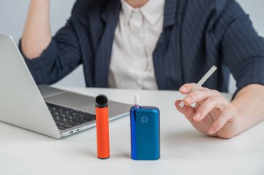 Bir kadın farklı sigara türleri gösterir. Bir e-sigara, tek kullanımlık bir tüp ve normal bir sigara.