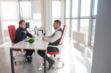 İki beyaz adam bir iş toplantısında iletişim kuruyor.