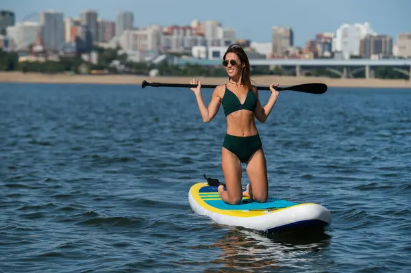 Gölde SUP sörf tahtası süren beyaz bir kadın. Yaz sporu