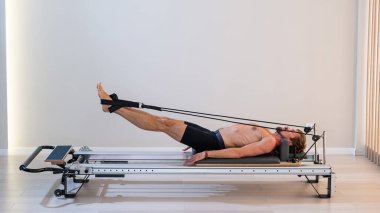 Reformcu üzerinde pilates yapan bir adam.