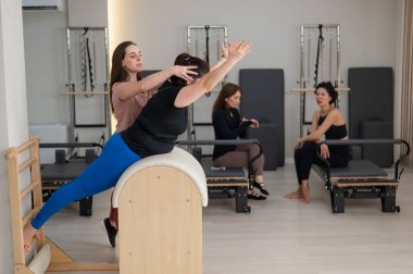 Pilates yapan üç kadın ve pilates yapan bir fıçı.