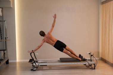 Reformcu üzerinde pilates yapan bir adam.