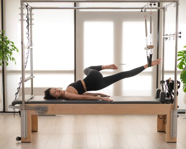 Asyalı kadın reformcuda pilates yapıyor.