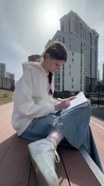 Açık havada kalemle çizim yapan beyaz bir kadın.