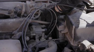 Beyaz adam bujileri değiştiriyor ve yüksek voltajlı kabloları söküyor.