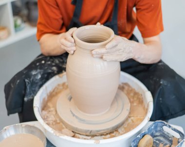 Çömlekçi elleriyle çömlekçi çarkında seramik vazo yaparken.