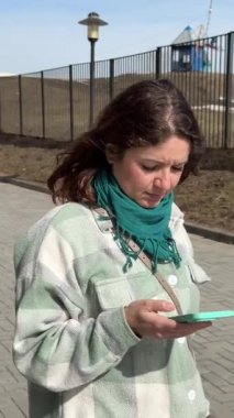 Beyaz kadın yürüyor ve akıllı telefon kullanıyor.