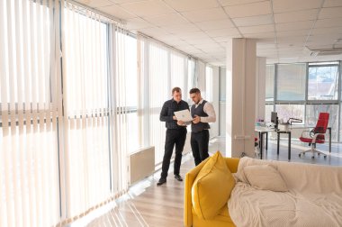 İki beyaz adam dizüstü bilgisayara bakıyor ve iş tartışıyorlar.