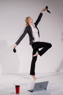 Beyaz arka planda iş elbisesiyle dans eden çıplak ayaklı balerin.