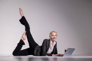 İş elbisesi giymiş bir balerin dizüstü bilgisayara poz verir ve kahve içer. Bilgisayar başında esnek bir kadın çalışıyor..