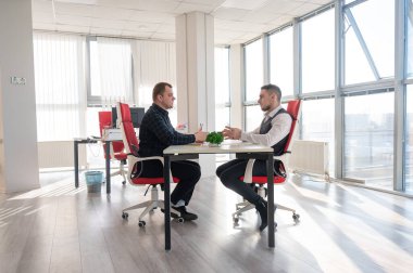 İki beyaz adam bir iş toplantısında iletişim kuruyor.