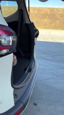 Beyaz kadın bagajın kapısını açtı ve Jack Russell Terrier köpeğini dışarı çıkardı.