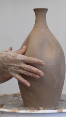 Çömlekçi ellerinin çömlekçi çarkında seramik sürahi yapmasının yakın çekimi. Dikey video