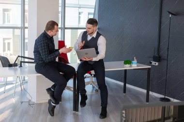 Ofiste iş tartışan iki beyaz adam. İşitme cihazı olan bir iş adamı.