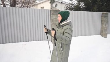 Kafkasyalı yaşlı kadın kışın İskandinav bastonlarıyla yürüyor