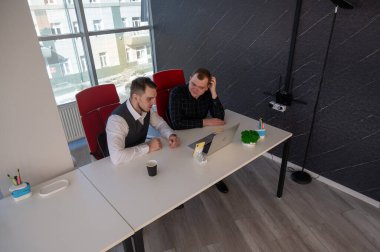 İki beyaz adam bir masada oturup iş tartışıyorlar.