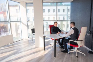 İki beyaz adam bir iş toplantısında iletişim kuruyor.