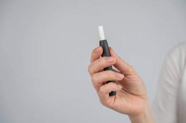 Kimliği belirsiz kadın elinde tütün ısıtma sistemi tutuyor.