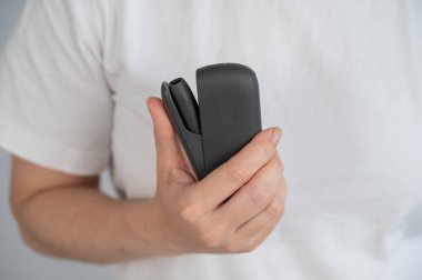 Bir kadın, tütün ısıtma sistemini şarj aletinden çıkarır. Elektronik sigara.