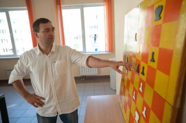 Duvarda duran beyaz adam manyetik satranç tahtası gösterisi yaptı.