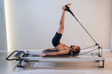 Reformcu üzerinde pilates yapan bir adam.