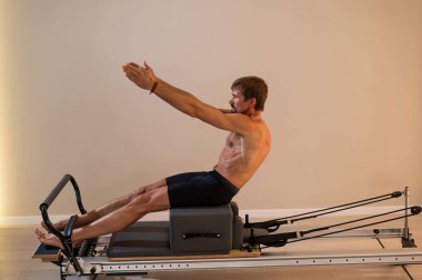 Reformcu üzerinde pilates yapan bir adam.