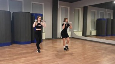 İki beyaz kadın dambıllarıyla saldırıyor.