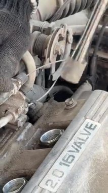 Beyaz adam arabadaki bujileri değiştiriyor.