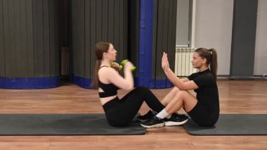 Karın egzersizi yapan iki beyaz kadın.